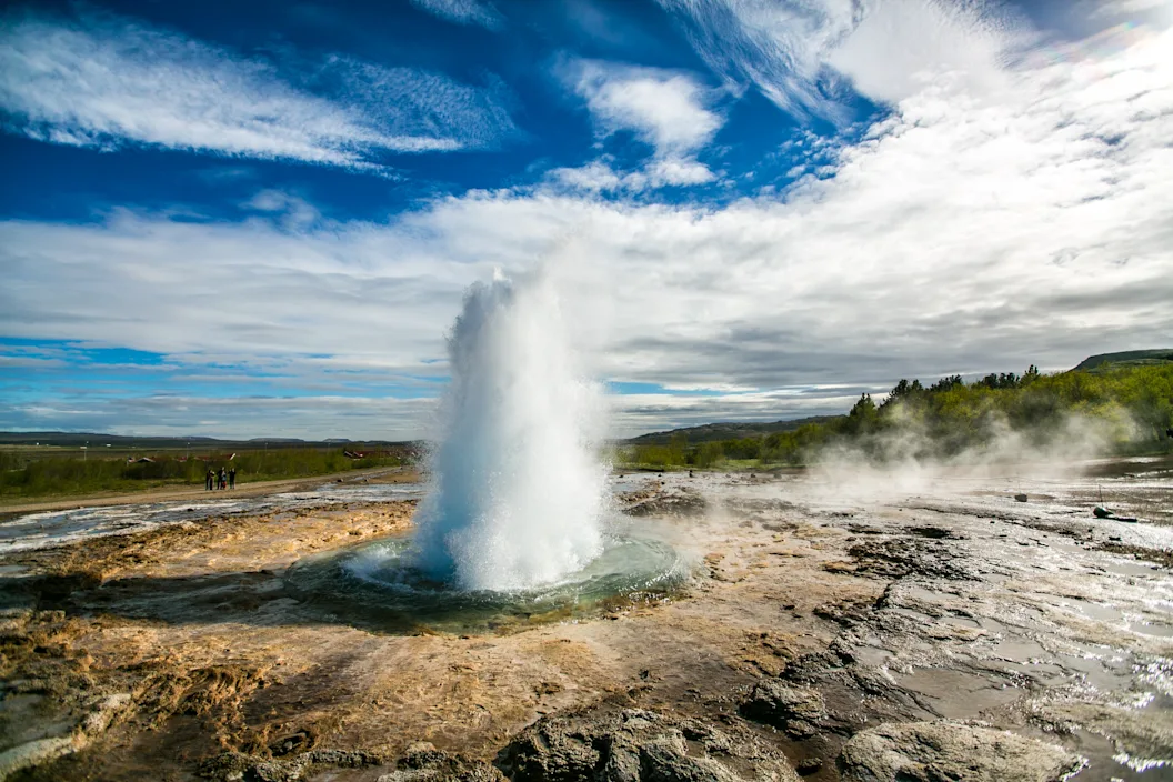 Espectacular géiser en erupción en Islandia, rodeado de un paisaje geotérmico característico de la isla.